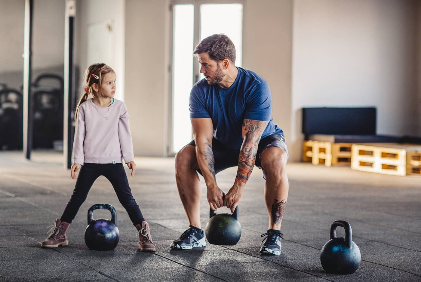 Un coach et une enfant à l’entraînement avec des kettlebells